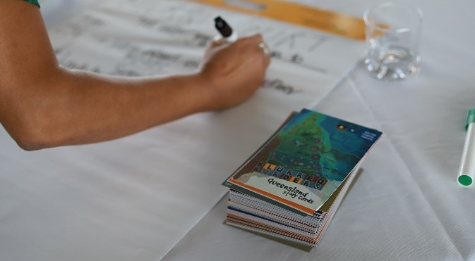 A hand taking notes next to a stack of Blurred Borders cards.