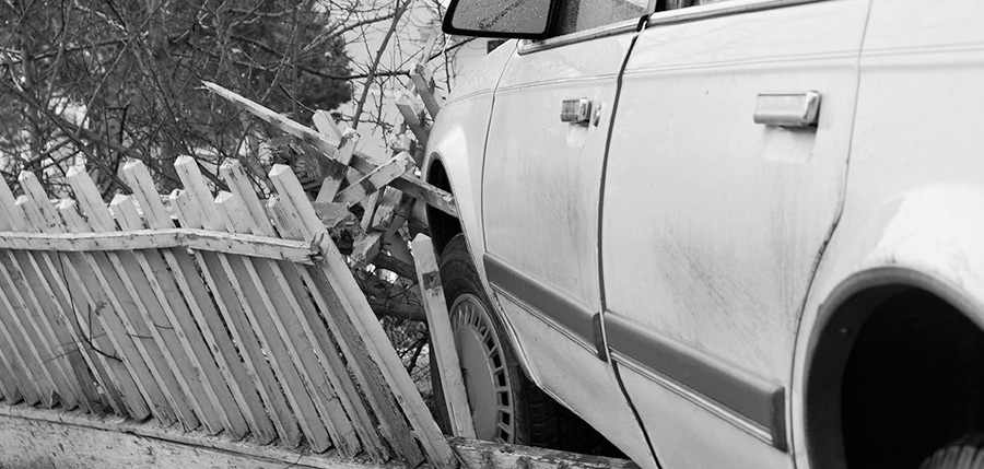 A photo of a car crashed through a picket fence