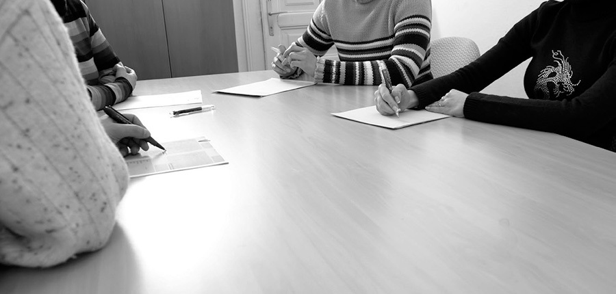 A photo of four people sitting around a table having a discussion. None of their faces are visible.