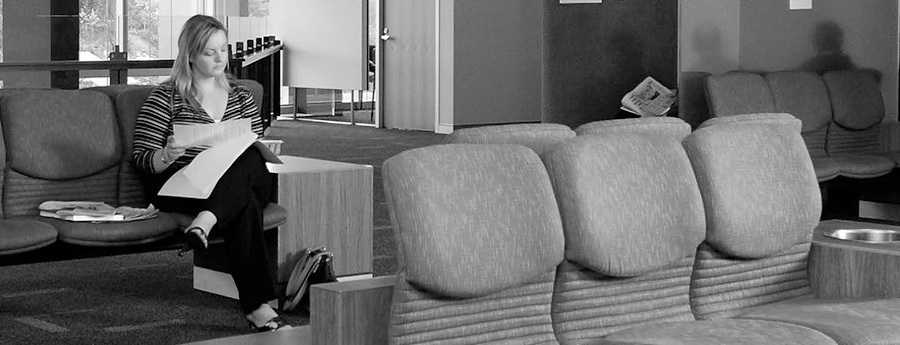 A photo of a woman filling out a form in a waiting room.