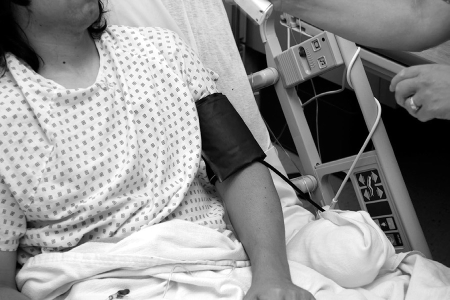 A photo of a person in a hospital bed connected to a heart monitor.