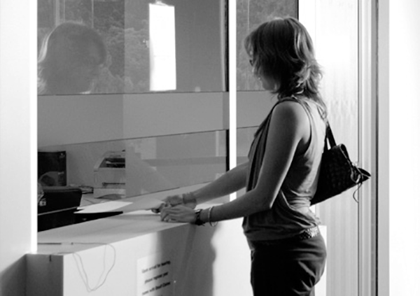 A woman stands at the service desk of a government building.